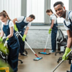 Professional commercial cleaning team in uniforms cleaning a modern office space with eco-friendly supplies and equipment.