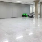Polished stone floor in a commercial lobby with a floor scrubber and cleaning products ready for use