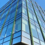 Sunlit glass facade of a modern commercial office building with clean, streak-free windows