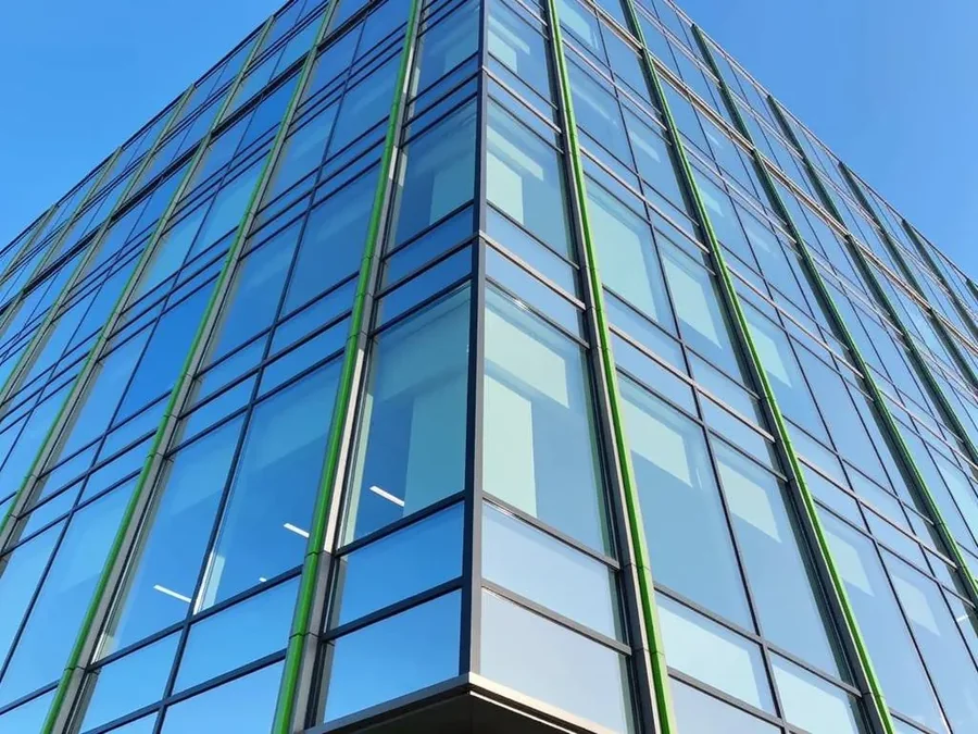 Sunlit glass facade of a modern commercial office building with clean, streak-free windows